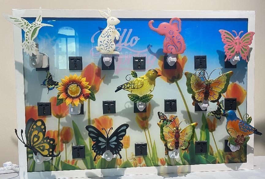 A blue backdrop wall hung with metal butterflies, dragonflies and sunflower pieces