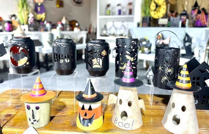 Halloween ceramic wax warmers and ghost lanterns lined up on a wooden bench